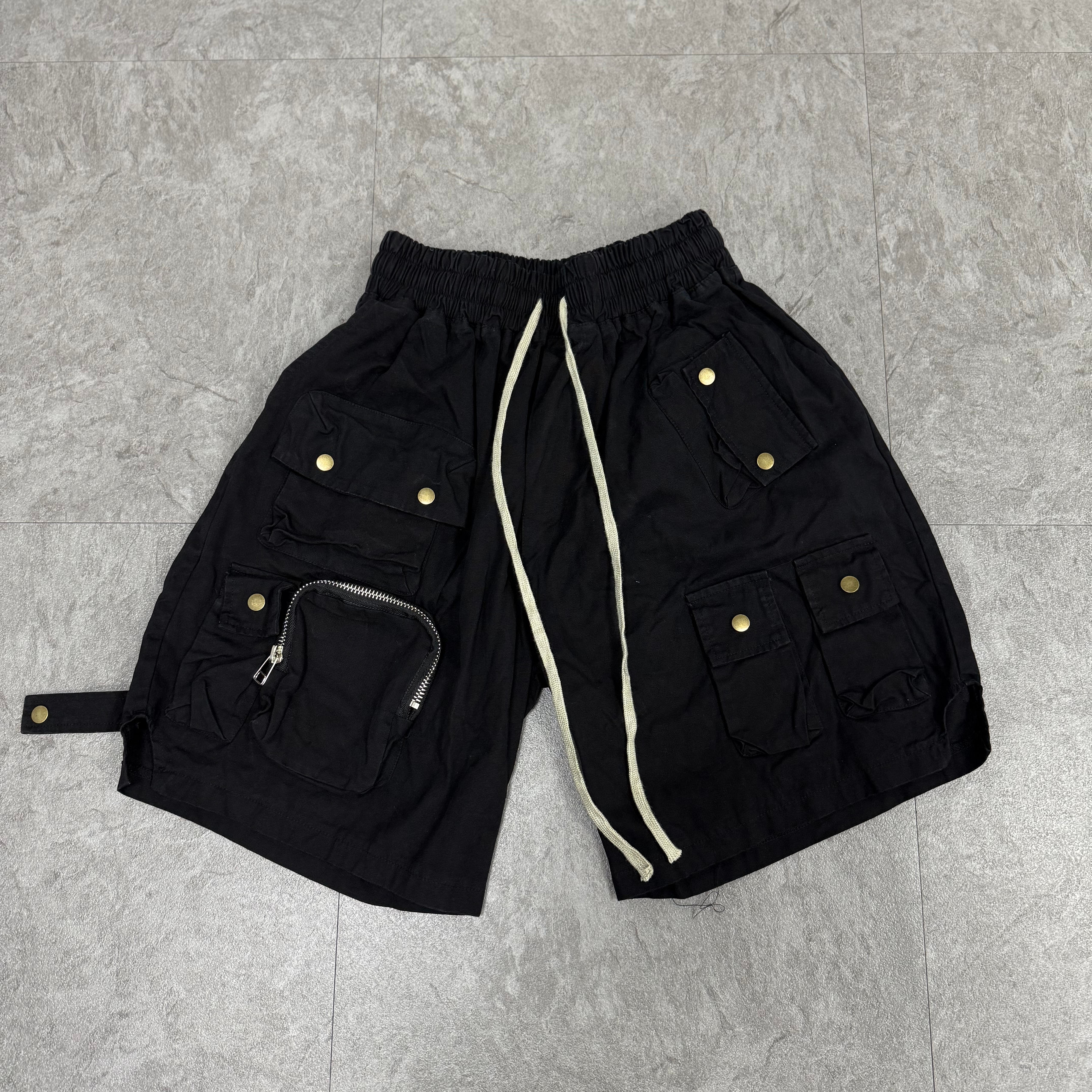 Black multi-pocket shorts fully laid out on floor
