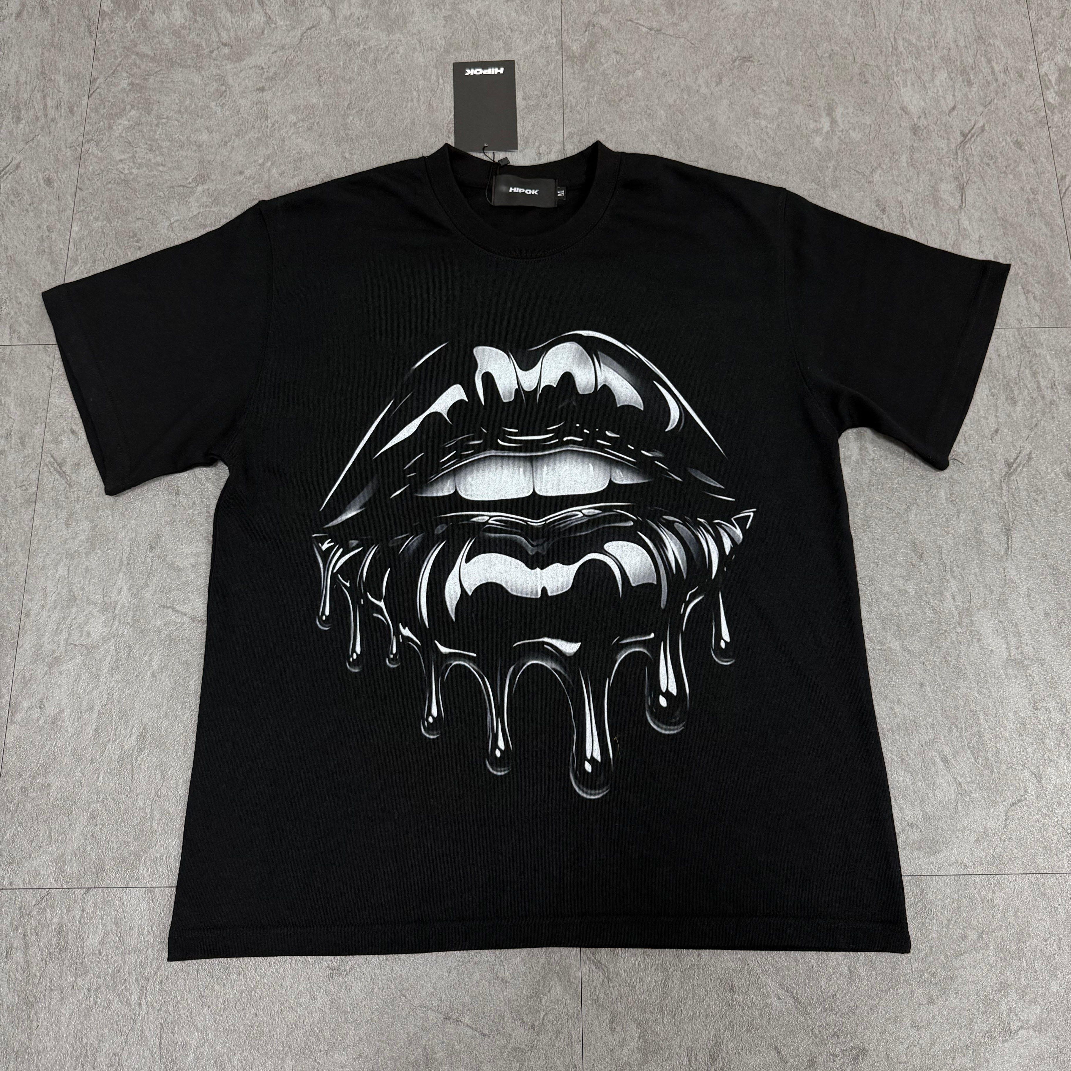 Front view of Drip Kiss black T-shirt laid flat on the floor